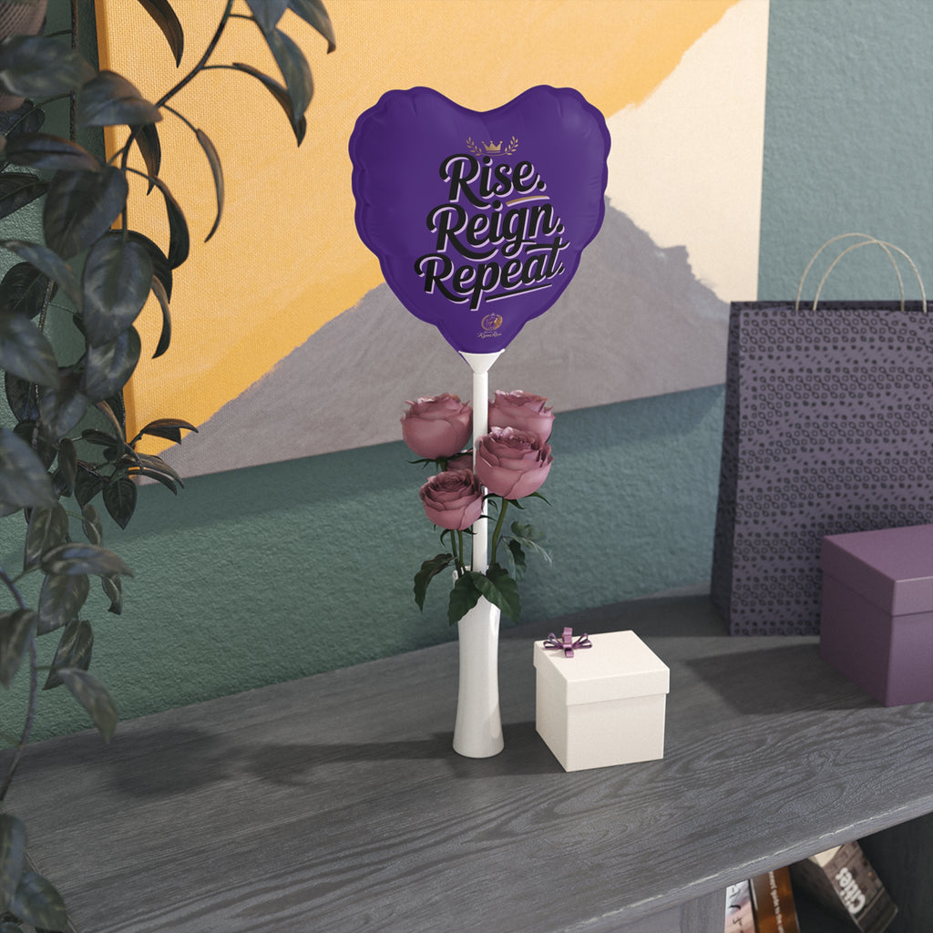 Purple balloon with 'Rise, Reign, Repeat' text, roses, and a white box on a table against a colorful wall.