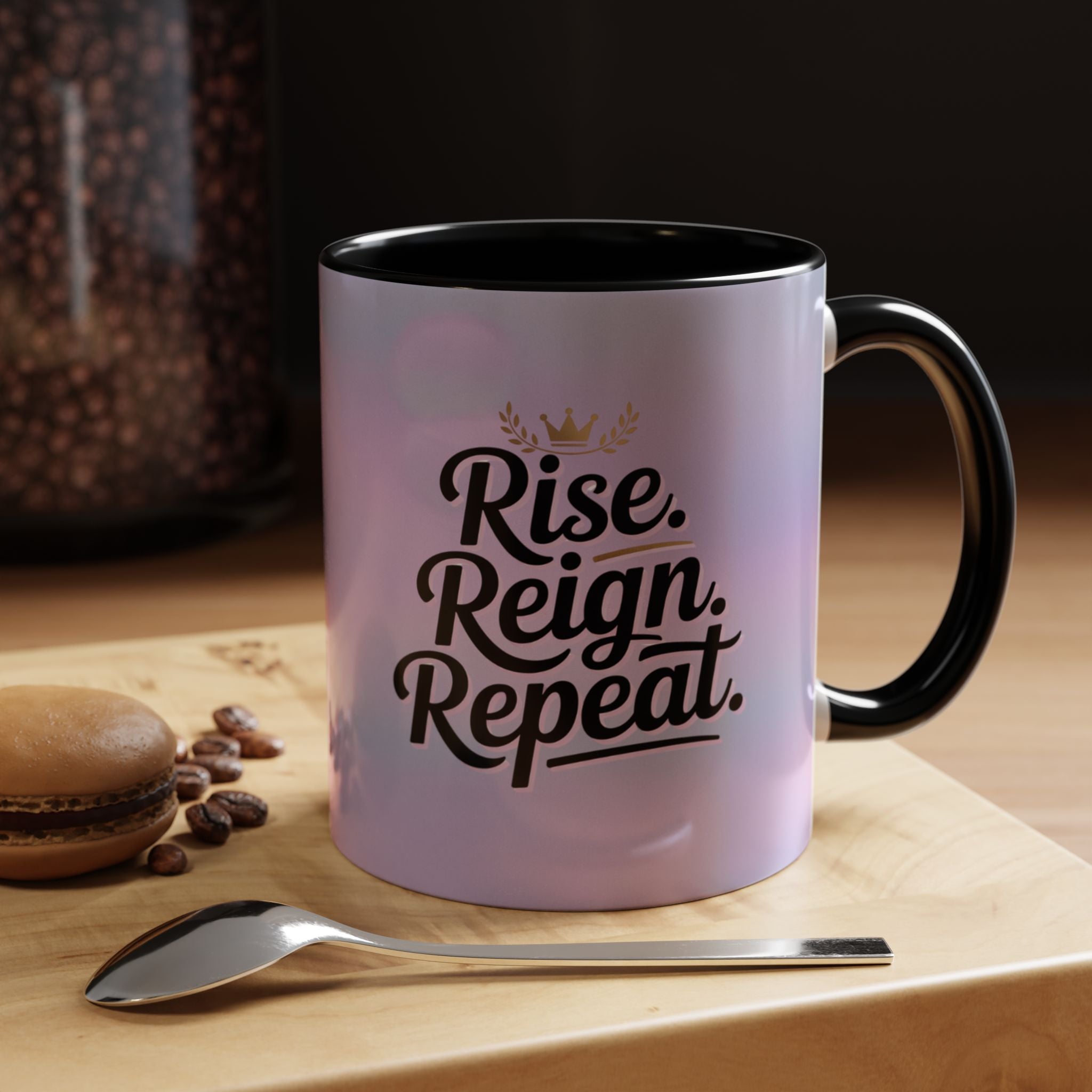 Mug with 'Rise. Reign. Repeat.' text on a wooden surface with coffee beans and a spoon.
