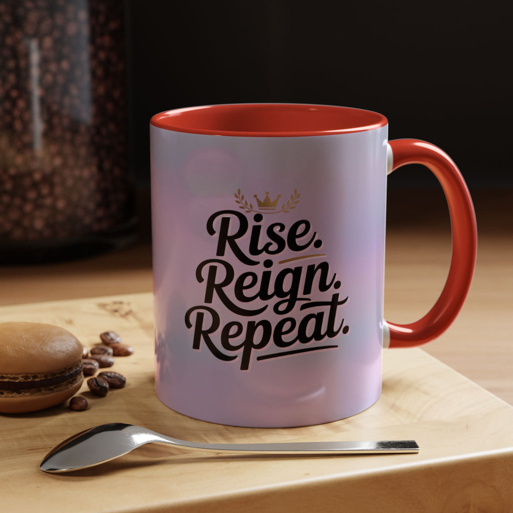 Mug with 'Rise. Reign. Repeat.' text on a table with coffee beans and a spoon.