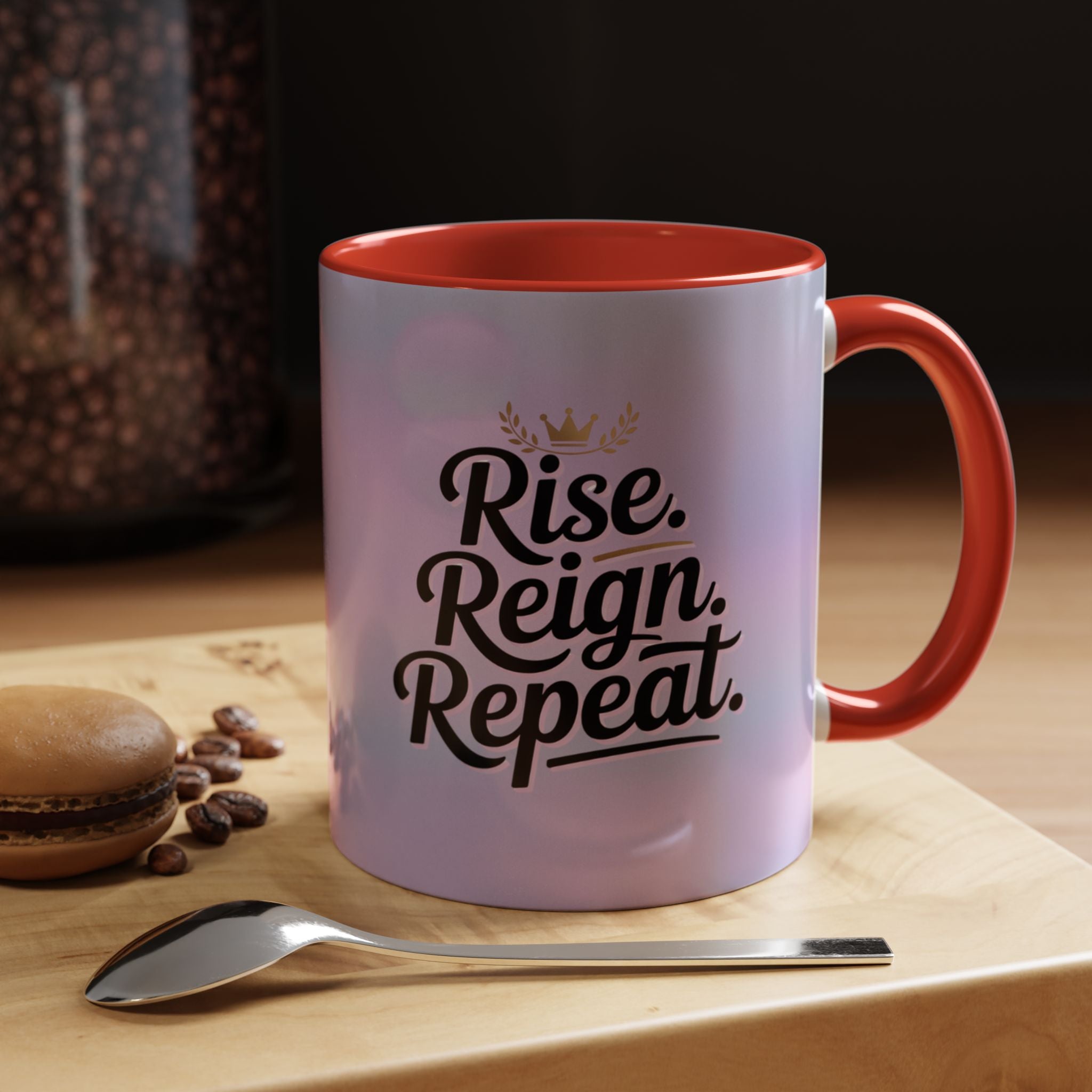 Mug with 'Rise. Reign. Repeat.' text on a table with coffee beans and a spoon.