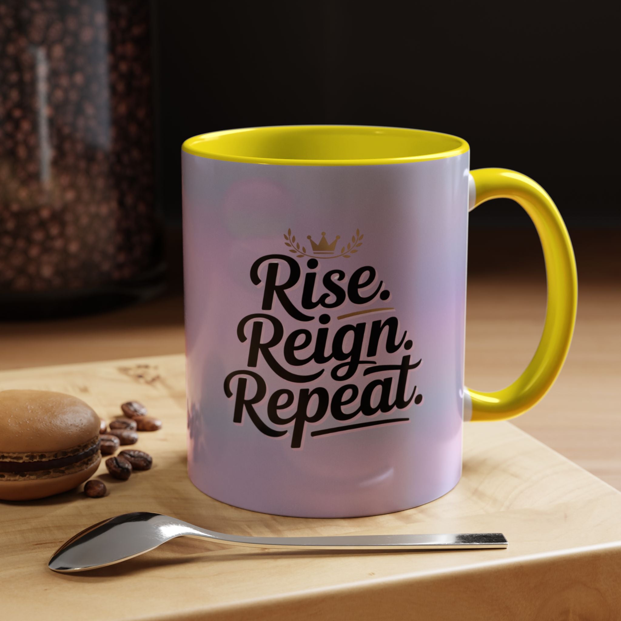 Mug with 'Rise. Reign. Repeat.' text on a wooden surface with coffee beans and a spoon.