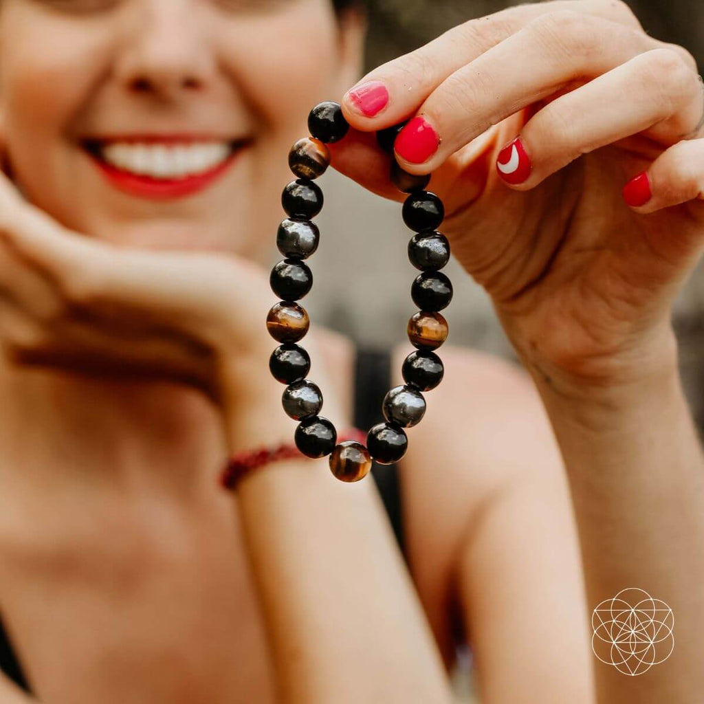 Person holding a black beaded bracelet with a blurred background