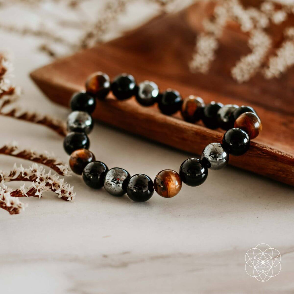 Beaded bracelet with black, brown, and silver beads on a wooden surface.