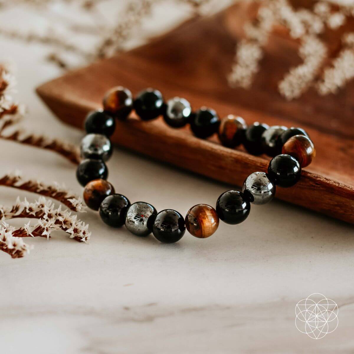 Beaded bracelet with black, brown, and silver beads on a wooden surface.